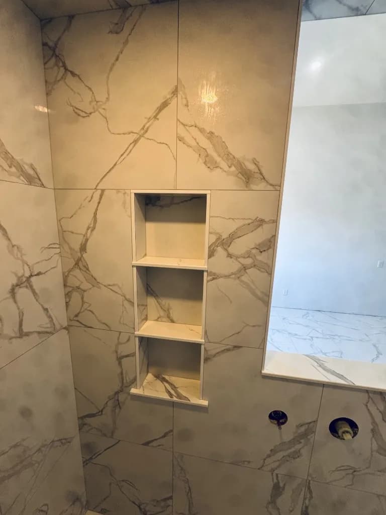 Custom recessed shower niche with precision marble-look tile work