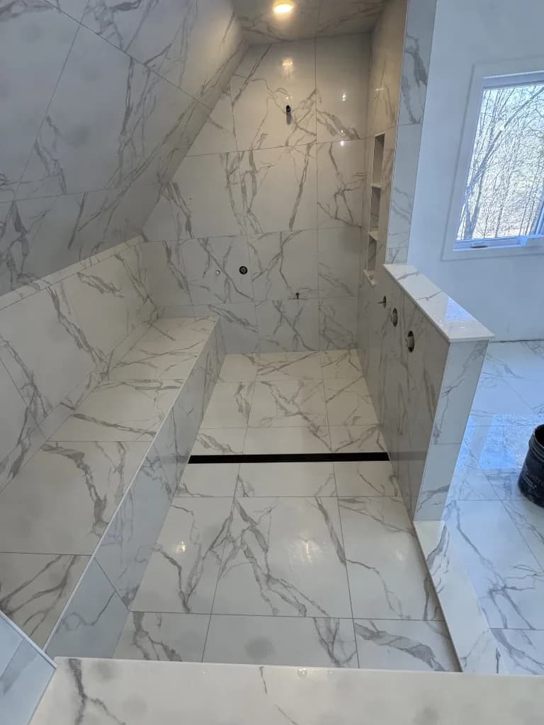 Curbless walk-in shower with integrated bench and marble-look porcelain tile