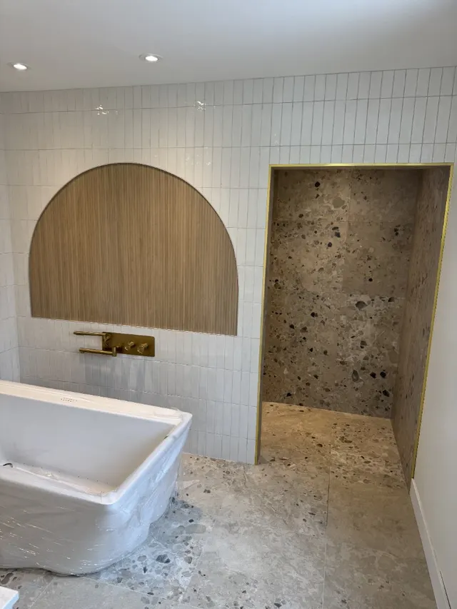 Surface Renaud – bathroom with wood arch feature and terrazzo shower