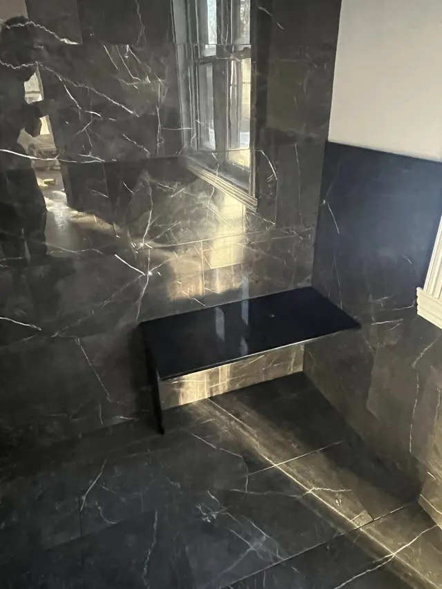 Surface Renaud – black marble tile shower with floating bench