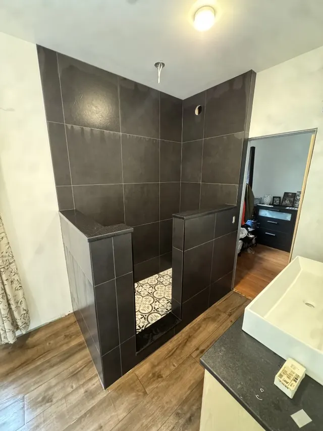 Surface Renaud – walk-in shower with dark walls and decorative floor tile
