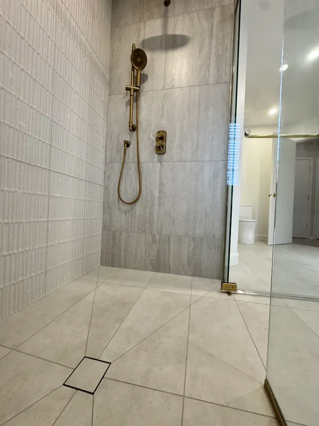 Surface Renaud – custom shower with gold fixtures and textured tile