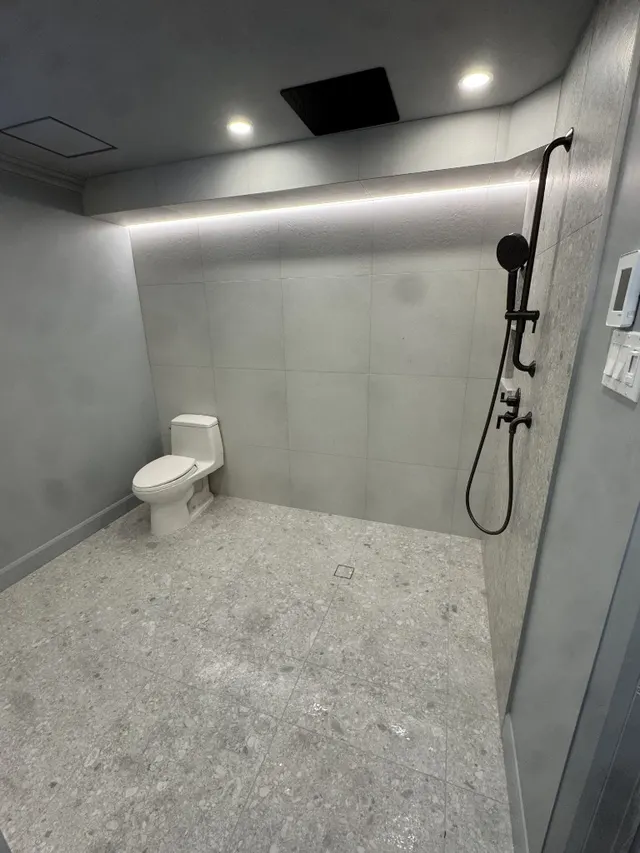 Surface Renaud – grey terrazzo wet room with matte black rainfall shower