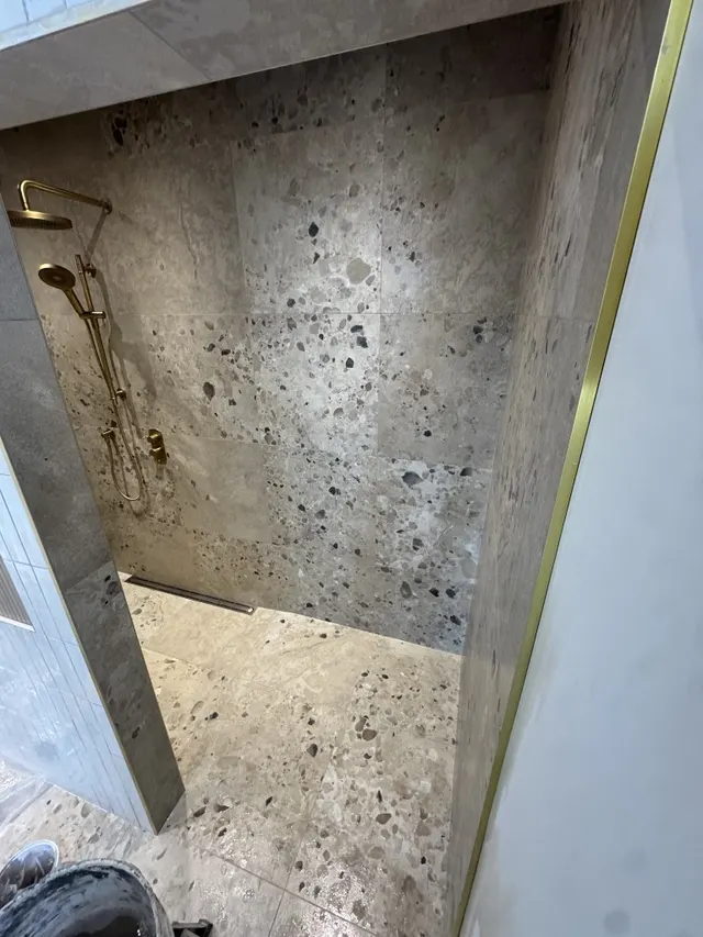 Surface Renaud – terrazzo tile shower with brushed gold fixtures