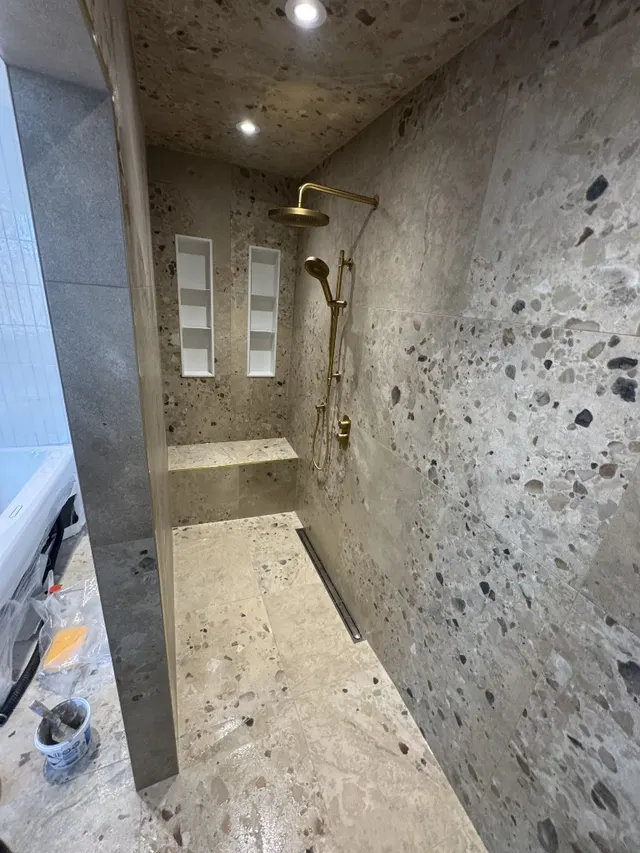 Surface Renaud – full terrazzo shower with gold rainfall fixtures